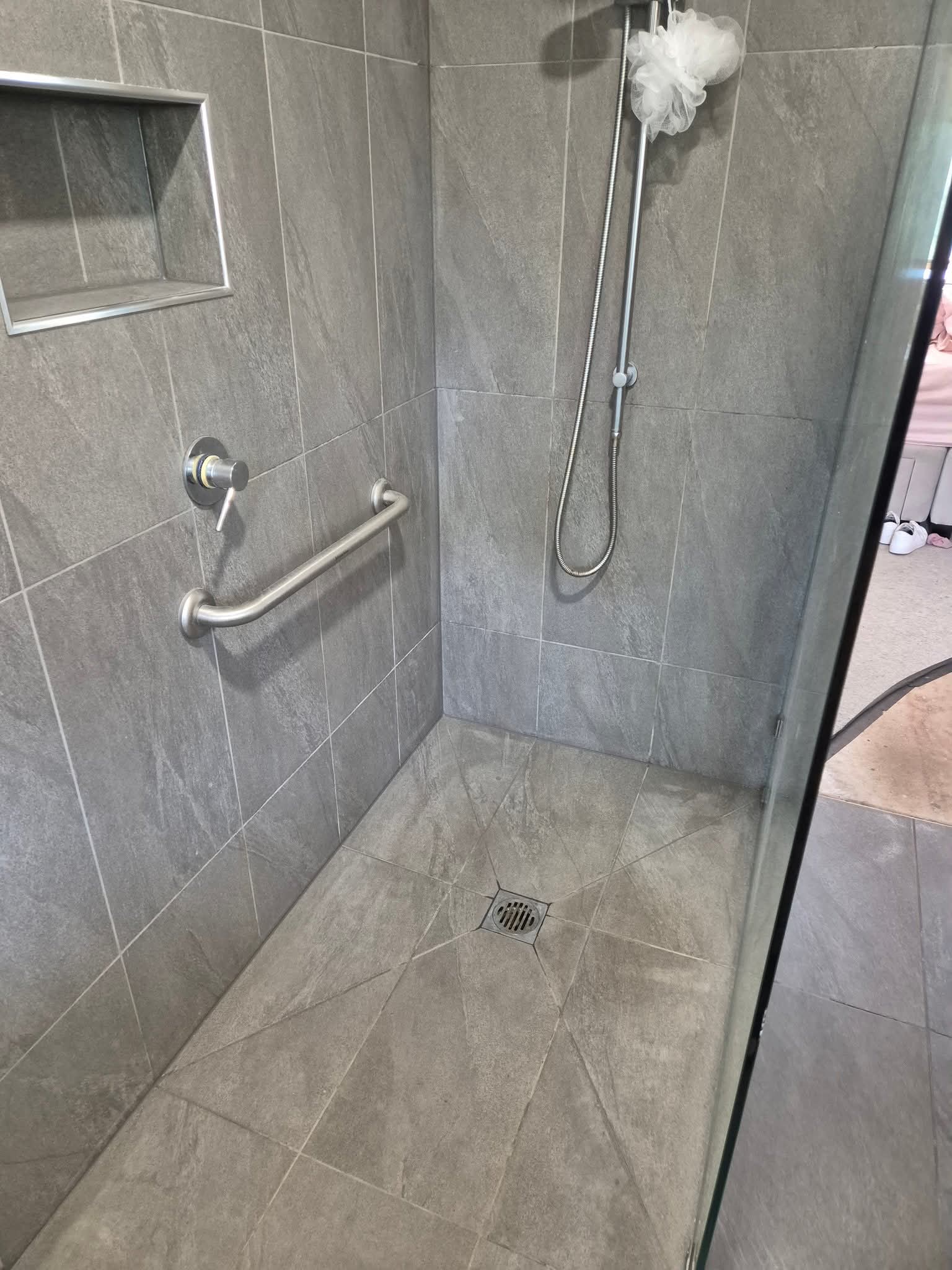 Modern tiled walk-in shower with a stainless steel grab bar.