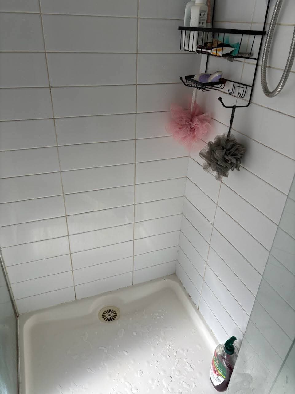 White-tiled shower with recessed storage rack.